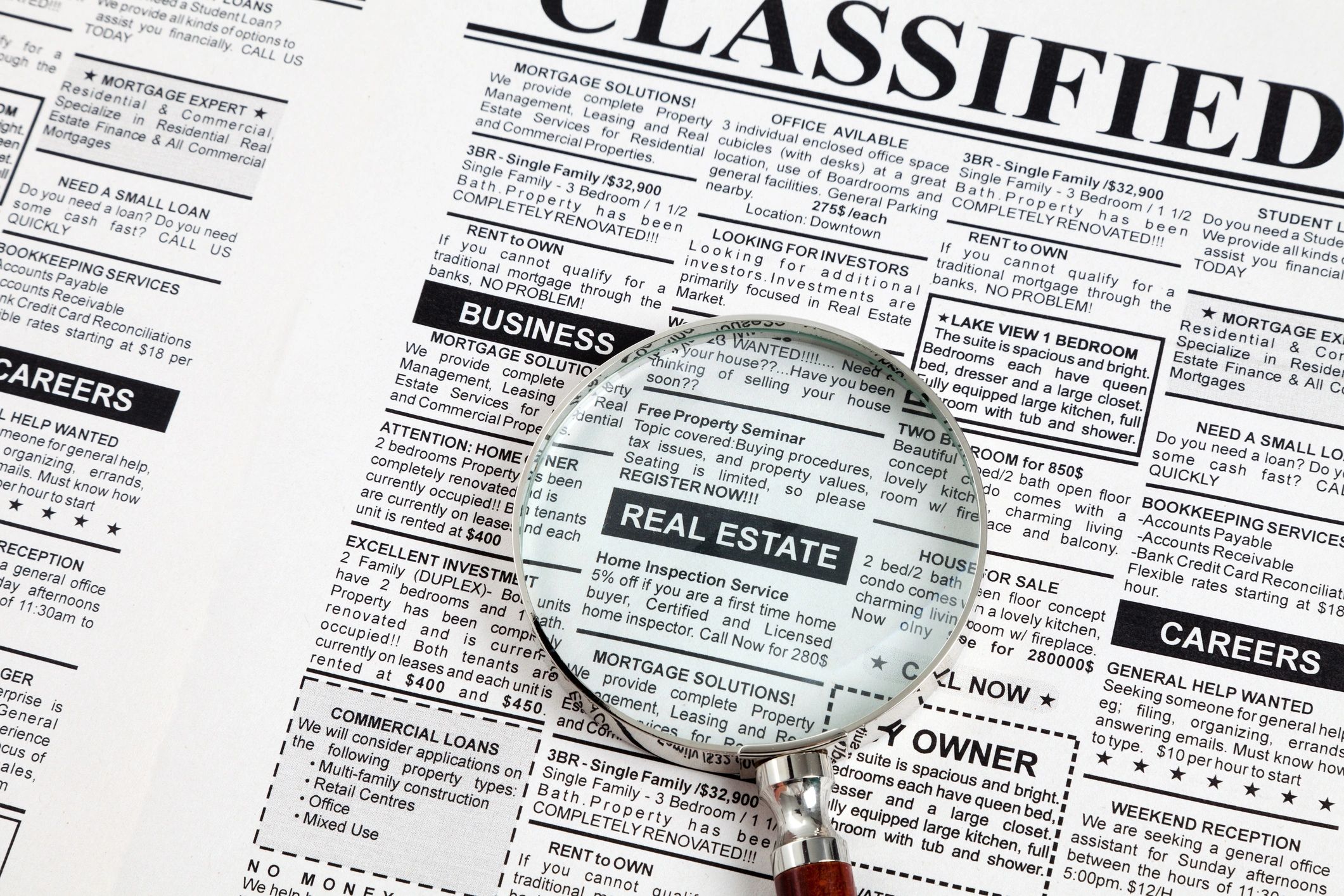A magnifying glass is on top of a classified ad.